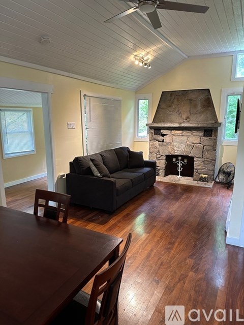 A living room with a grey couch and a stone fireplace.