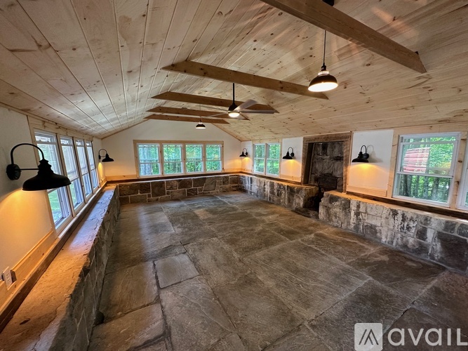 A spacious room with a stone floor and wooden ceiling.
