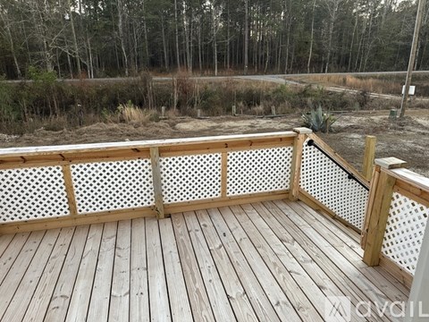 A wooden deck with a lattice fence and a view of a wooded area.