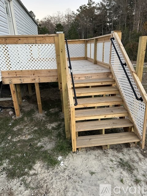 A wooden staircase with a black railing leads up to a deck.