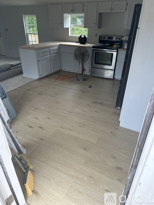 A kitchen with white cabinets and a fan on the counter.
