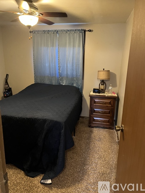 A bedroom with a bed, dresser, and ceiling fan.