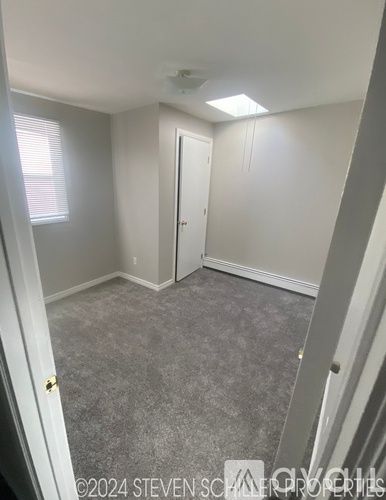 A bedroom with a carpeted floor and a window with blinds.