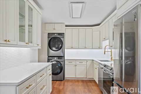 A kitchen with white cabinets and a washing machine and dishwasher.
