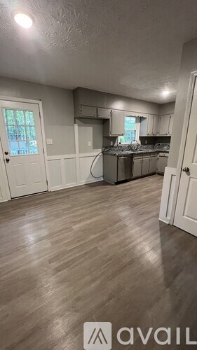 A spacious room with a ceiling fan and a refrigerator.