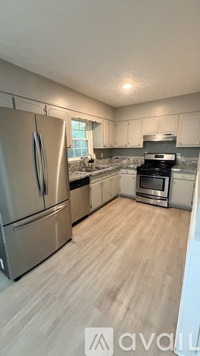 A kitchen with a refrigerator, oven, and stove top.
