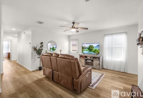 A living room with a brown sofa and a flat screen TV.