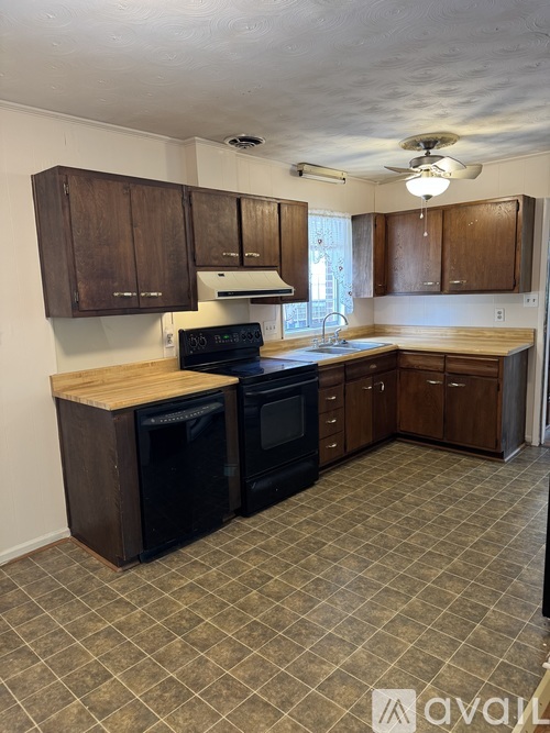 A kitchen with wooden cabinets and black appliances.