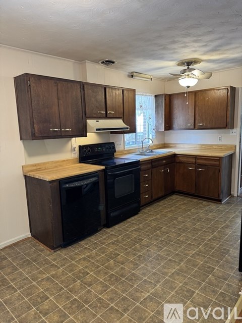 A kitchen with wooden cabinets and black appliances.