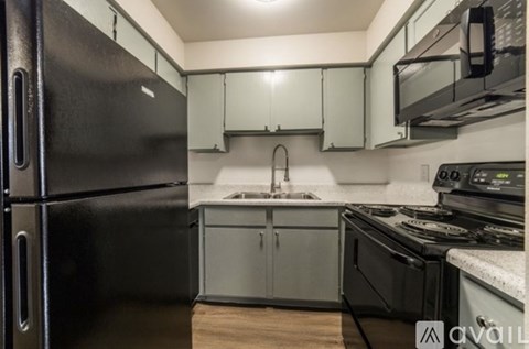 A kitchen with a black refrigerator and stove top oven.