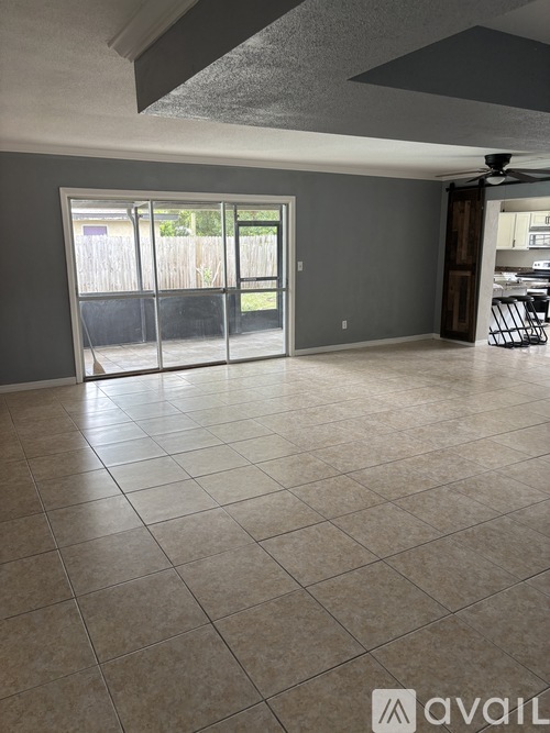 A spacious room with a tiled floor and a sliding glass door leading to a backyard.