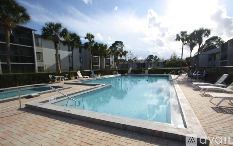A swimming pool surrounded by a brick patio and palm trees.