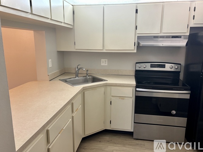 A kitchen with white cabinets and a black refrigerator.