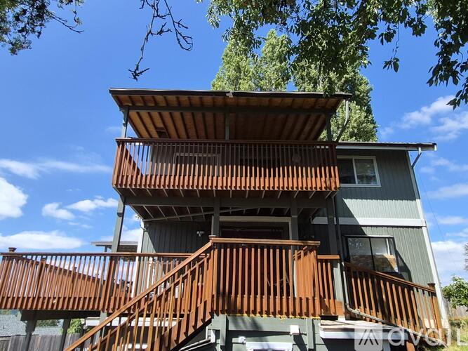 A house with a wooden deck and stairs leading to the second floor.