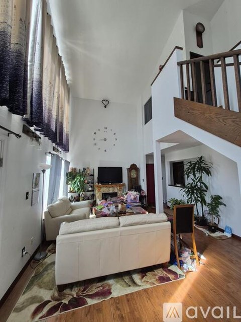 A living room with a white couch and a wooden staircase.