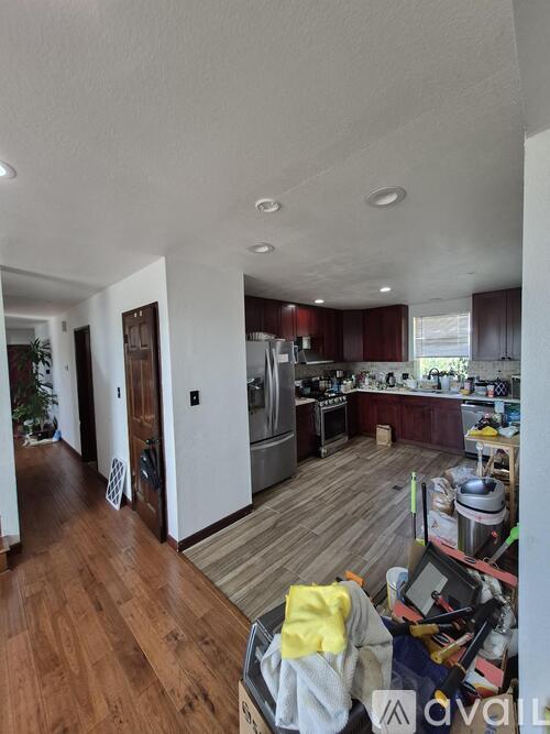 A kitchen with wooden floors and a messy counter.