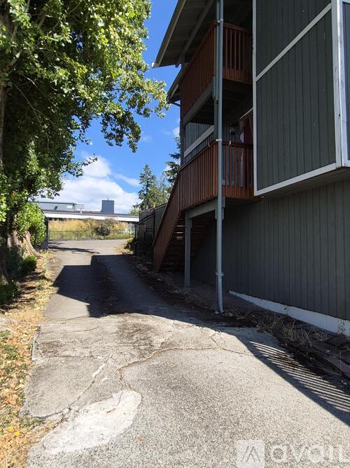 A concrete pathway leads to a building with a balcony.