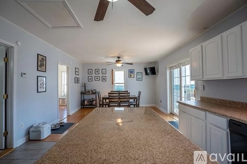 A living room with a brown carpet and a ceiling fan.