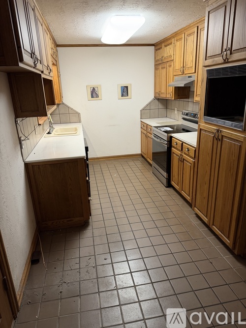 A kitchen with wooden cabinets and a tiled floor.