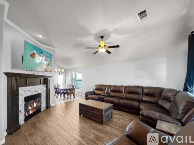 A living room with a fireplace and a brown leather couch.