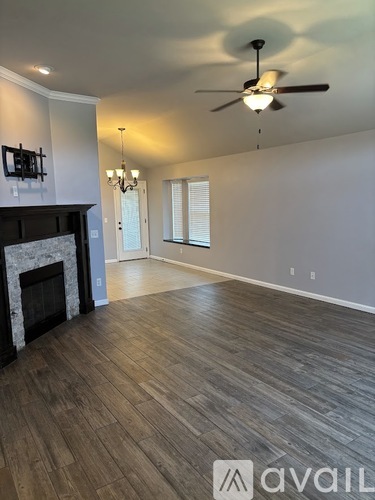 A spacious room with a fireplace and wood flooring.