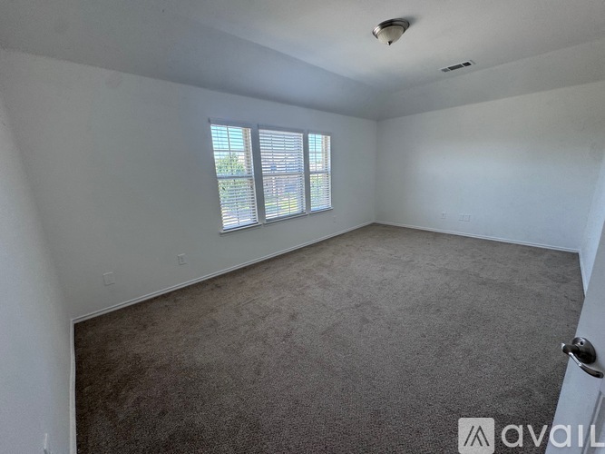 A room with a carpeted floor and a window with blinds.