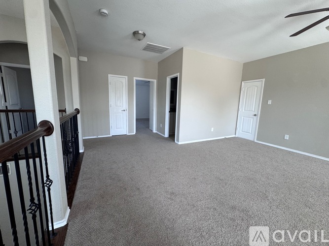 A spacious living room with a carpeted floor and a ceiling fan.