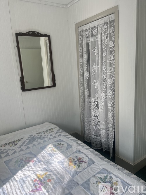 A bedroom with a bed, a mirror, and a curtain.