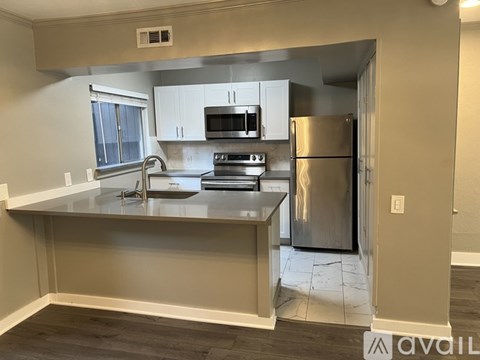A kitchen with a stainless steel refrigerator and a microwave above the stove.