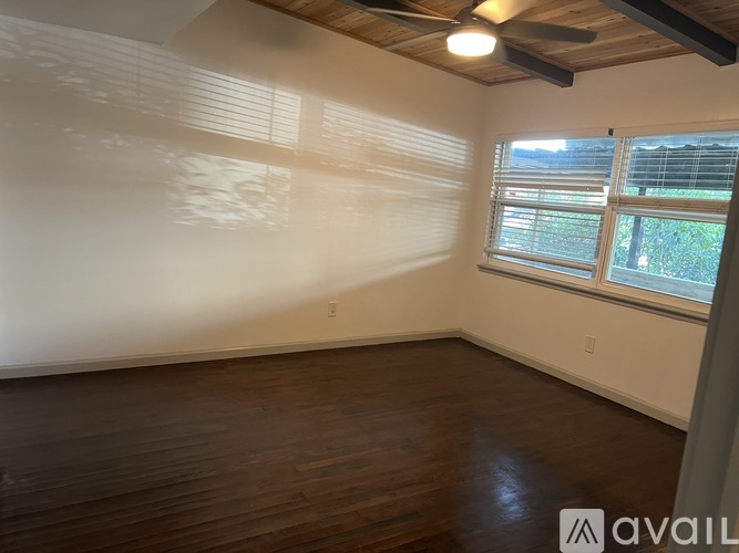 A room with wooden floors and a window with blinds.