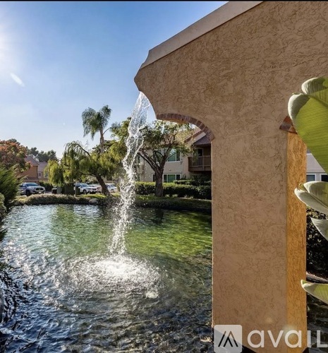 A fountain in a pool surrounded by a wooden deck and palm trees.