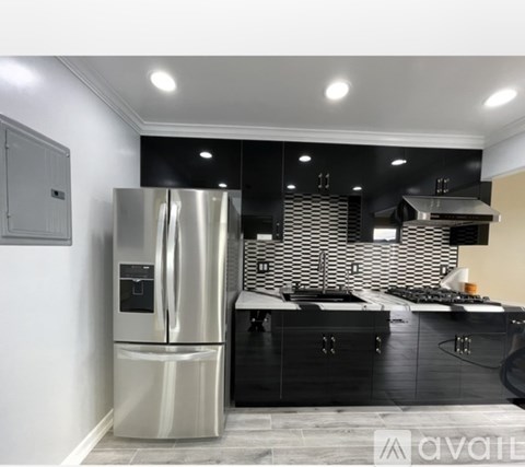 A modern kitchen with a stainless steel refrigerator and black cabinets.