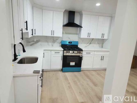 A kitchen with white cabinets and a blue stove top oven.