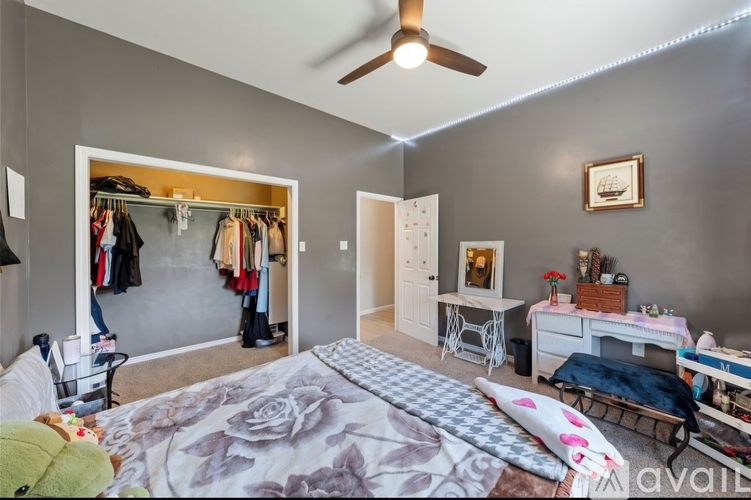 A bedroom with a large bed and a closet with clothes hanging.