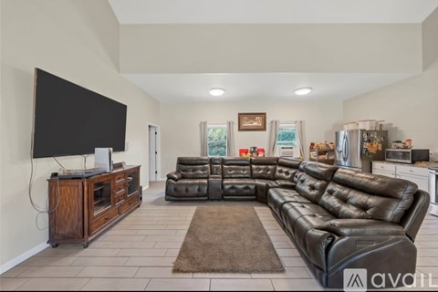 A living room with a black leather couch and a wooden entertainment center.