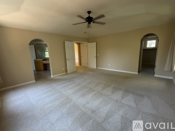 A spacious room with a carpeted floor and a ceiling fan.