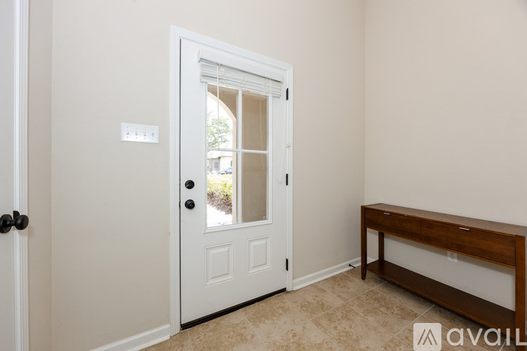 A white door with a black handle is in a room with a bench.
