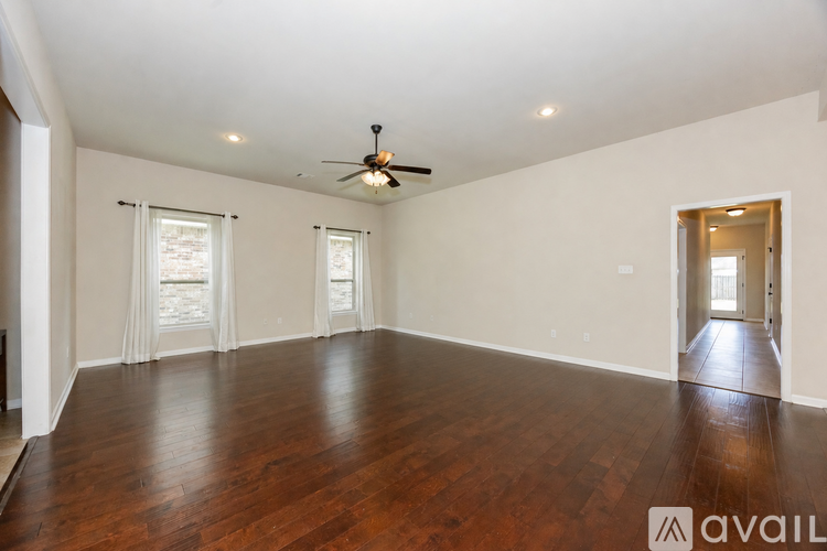 A spacious room with wooden floors and a ceiling fan.