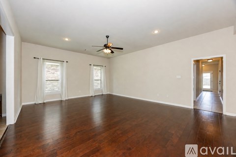 A spacious room with wooden floors and a ceiling fan.