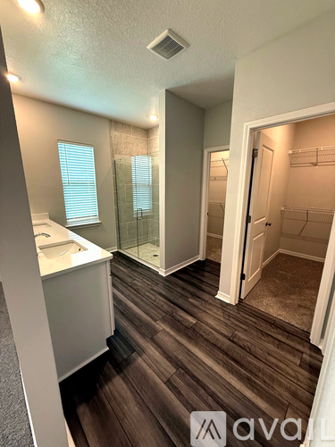 A bathroom with a sink, mirror, and wooden floors.
