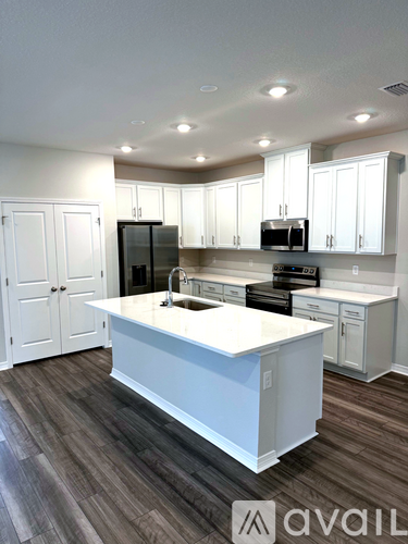 A kitchen with white cabinets and a white island.