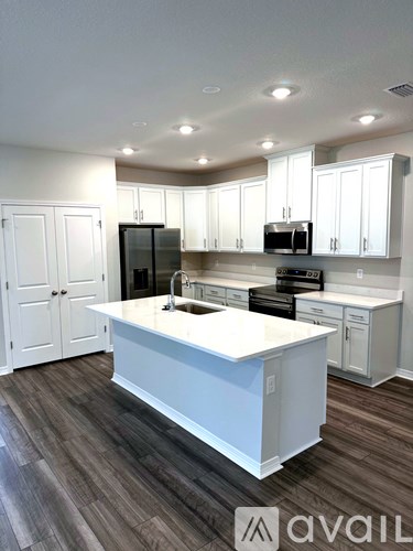 A kitchen with white cabinets and a white island.