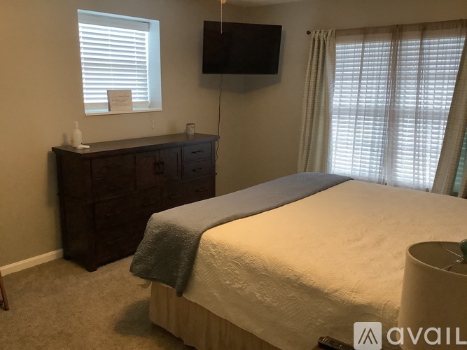A bedroom with a bed, dresser, and window.