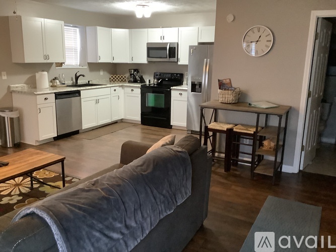 A kitchen with white cabinets and a grey couch.