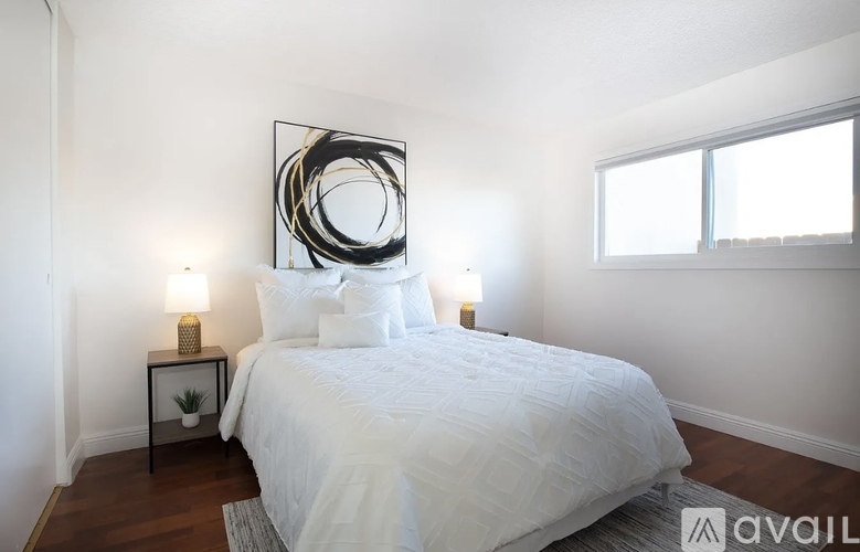 A bedroom with a large bed and a large abstract painting above it.