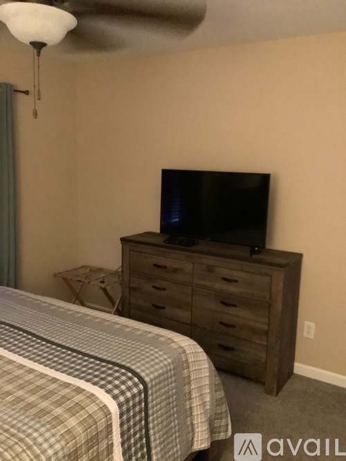 A bedroom with a bed, a dresser, and a television.