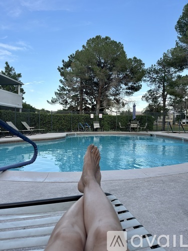 A person is relaxing by a pool with their feet in the water.