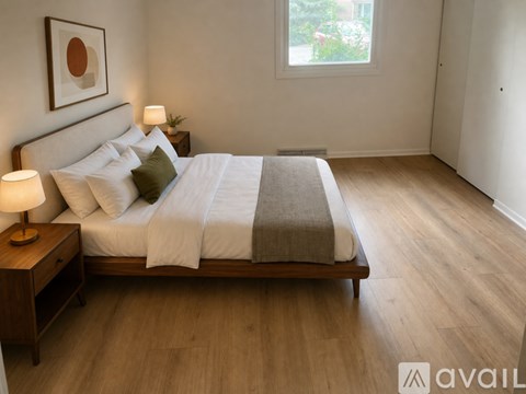 A bedroom with a large bed and a lamp on a nightstand.