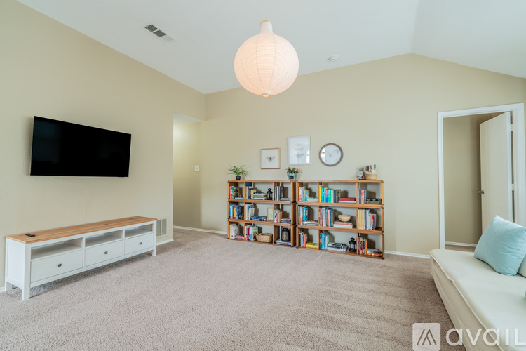 A living room with a television, bookshelves, and a bench.