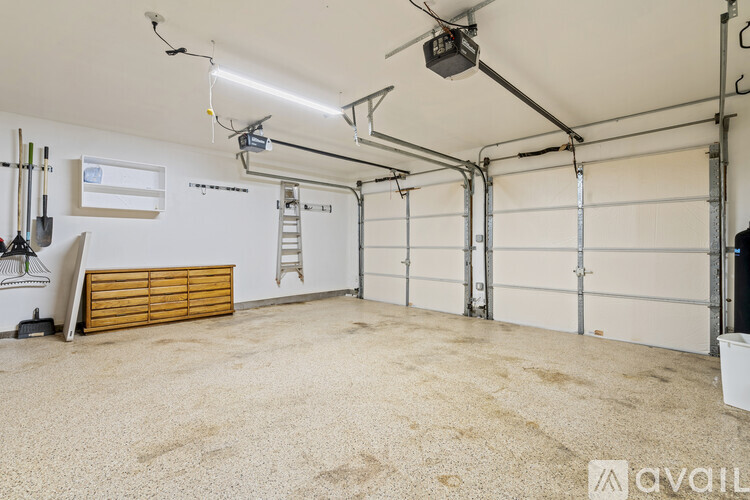 A spacious garage with a ladder and a shovel on the left side.